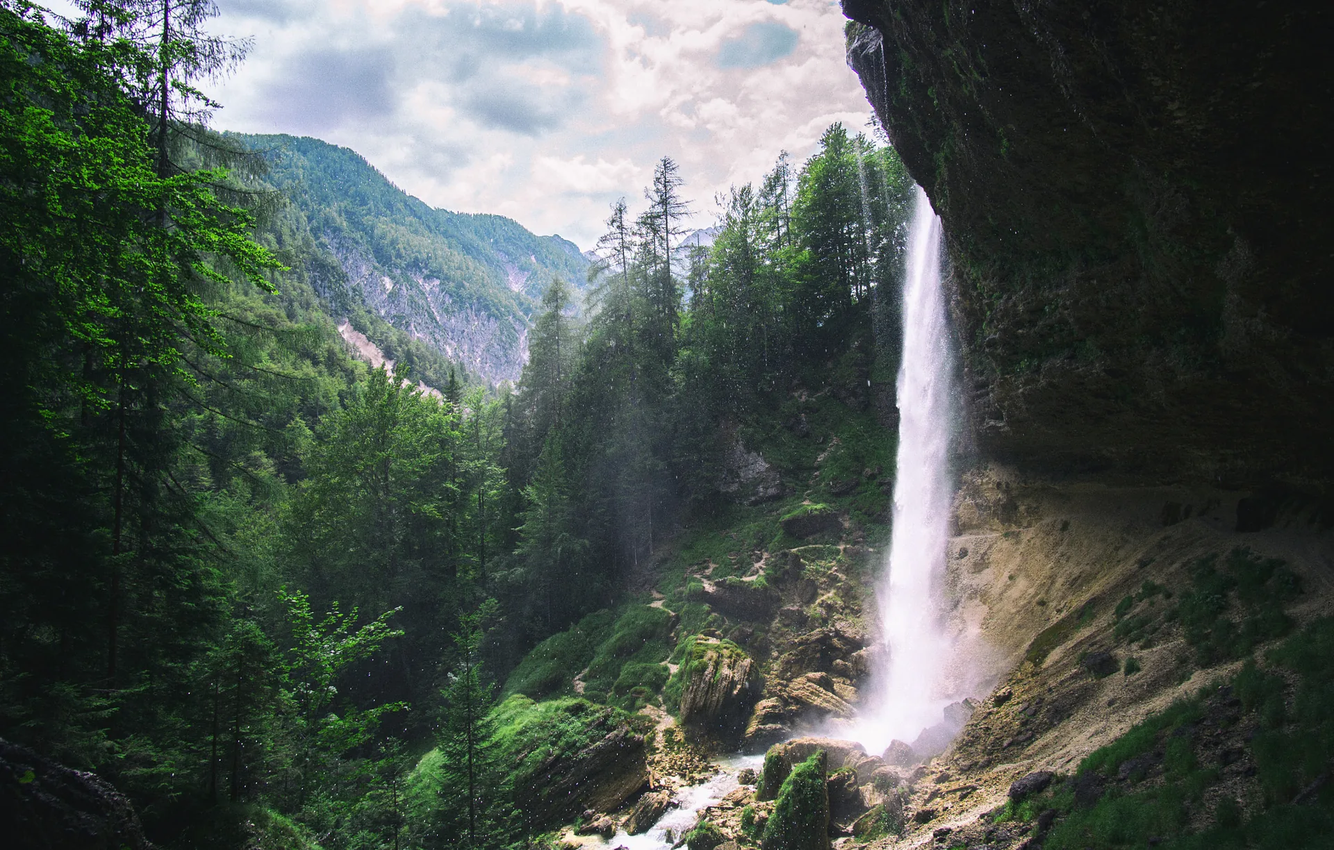 A valley in the Julian Alps, a waterfall falling from the cliffs above the forest